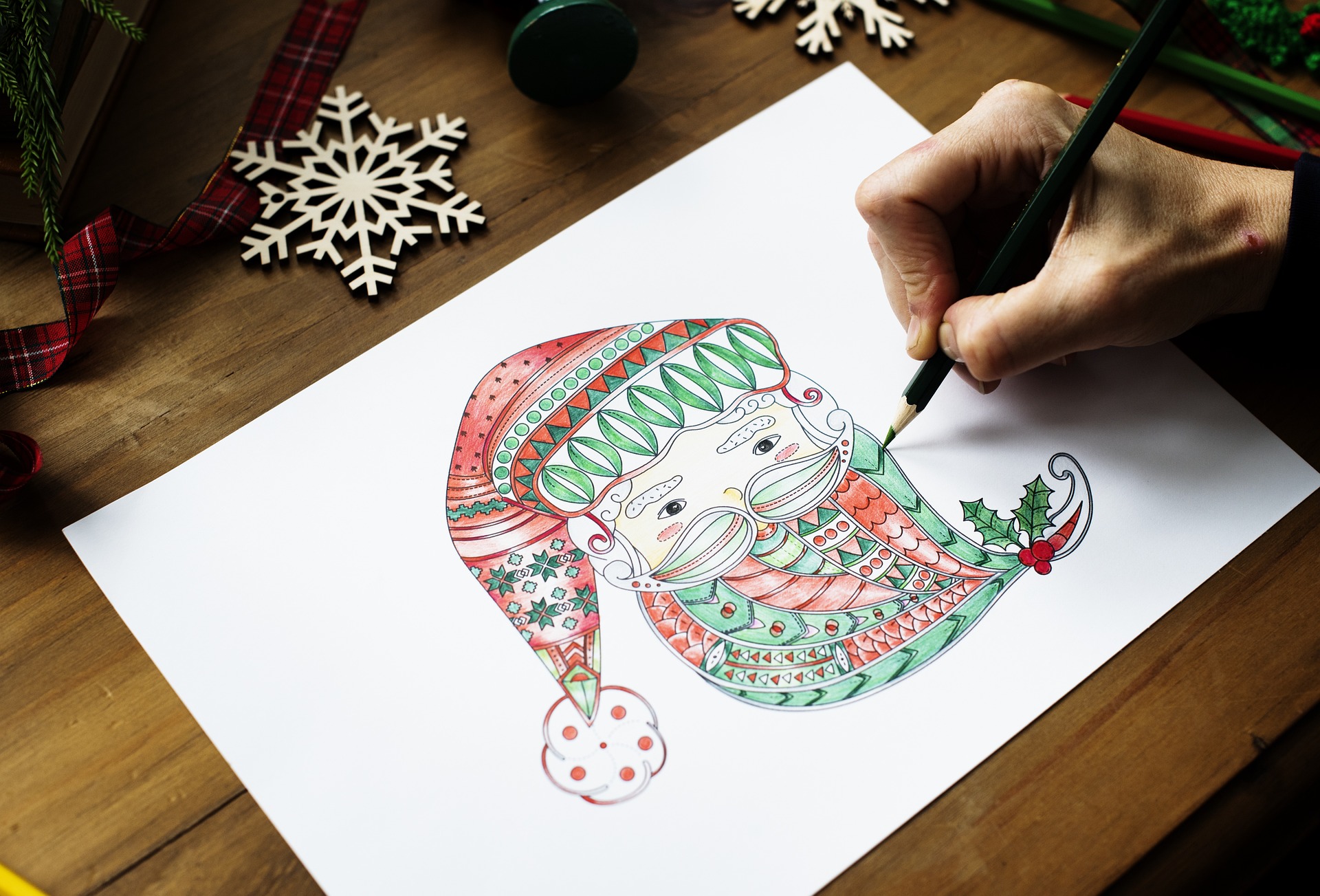 Person coloring a holiday illustration on paper